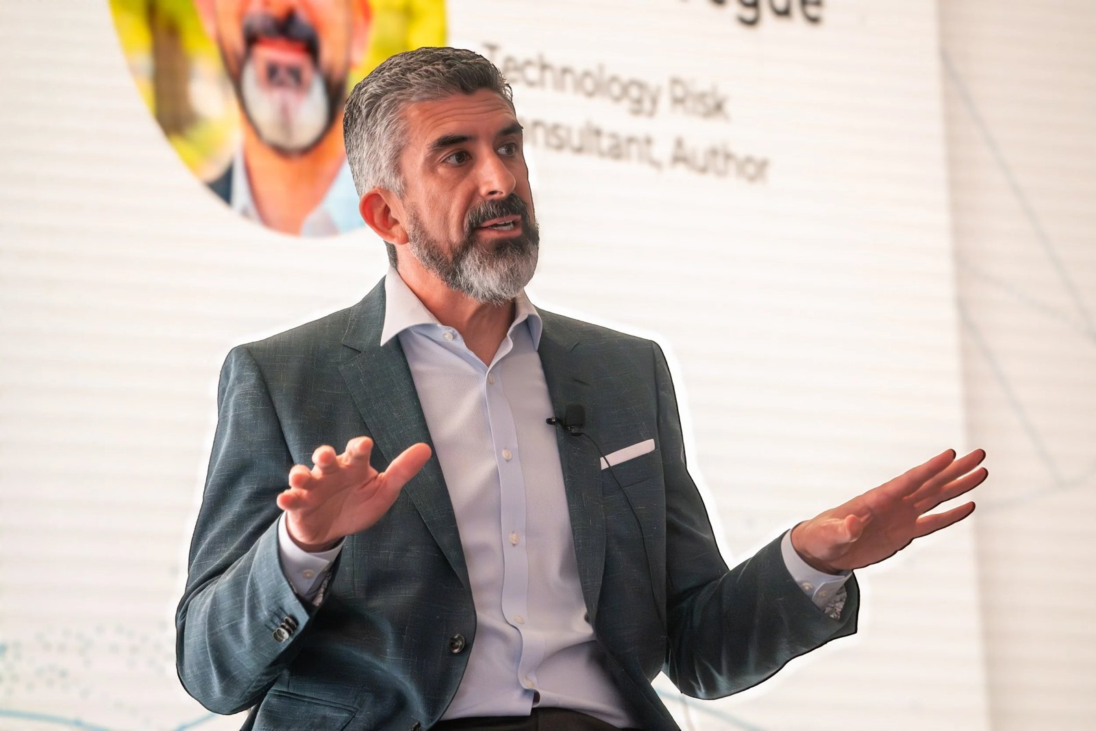 Tony Martin-Vegue speaking on a conference stage, gesturing with both hands